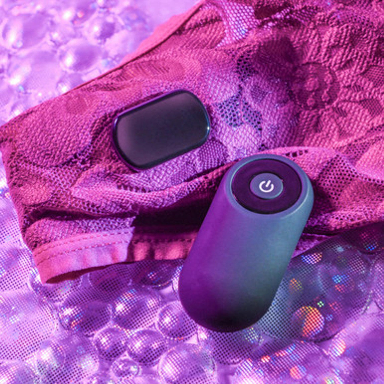 Two electronic Gender X Our Undie Vibe on a glittery purple surface