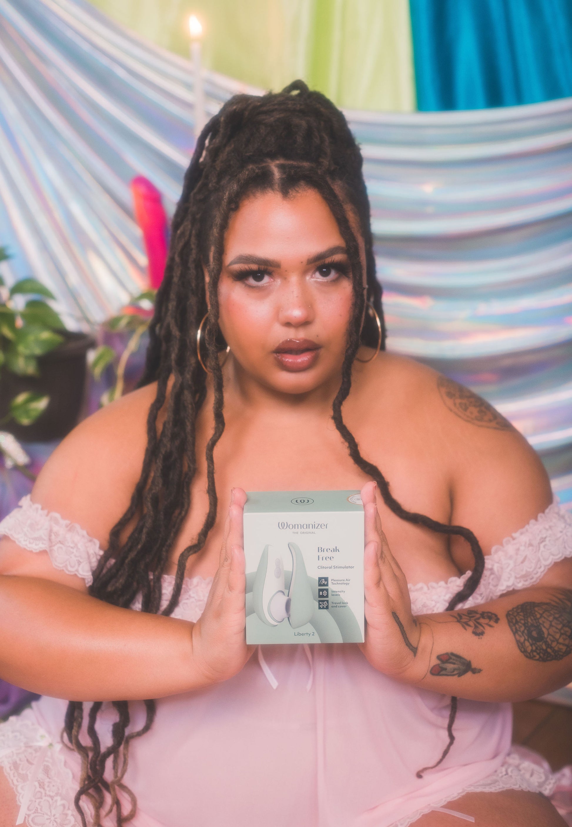 Woman holding a product box of Womanizer Liberty 2 against a colorful background