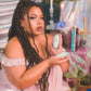 Woman holding a green Womanizer Liberty 2 in a decorative indoor setting with plants and candles.