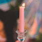 Hand holding a pink candle in a glass holder with blurred background