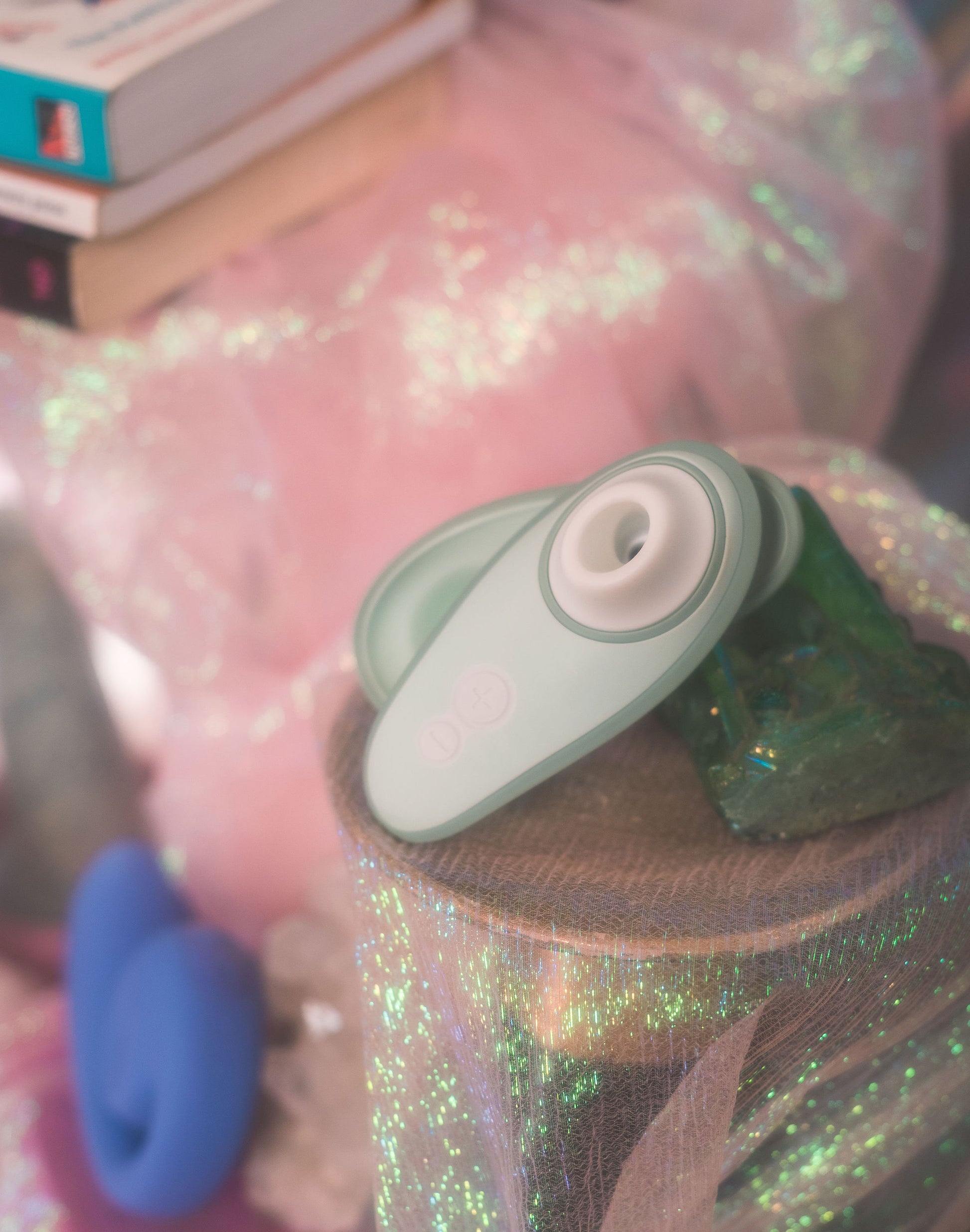 Close-up of a green and gray Womanizer Liberty 2 with a pink glittery background