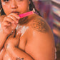 Woman with tattoos holding a lit candle against a colorful background