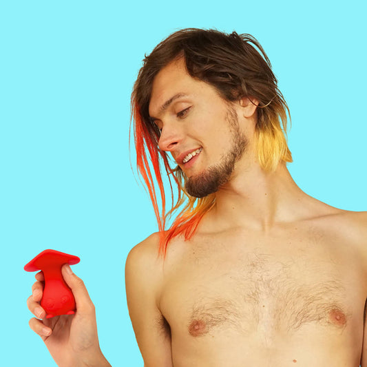 person with dyed hair holding a red vibrator against a blue background