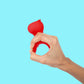 Hand holding a red silicone vibrator against a blue background