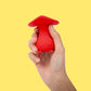 Red silicone mushroom toy held in a hand against a yellow background