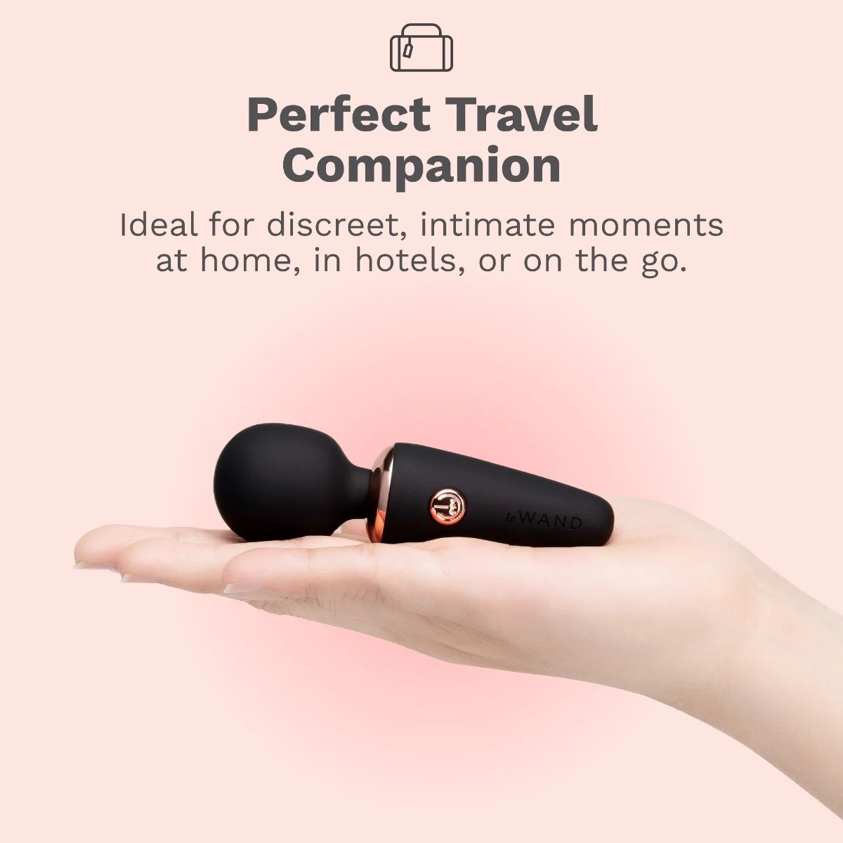 Black Le Wand Mini Micro Wand held in a hand with text describing it as a 'Perfect Travel Companion' on a pink background.