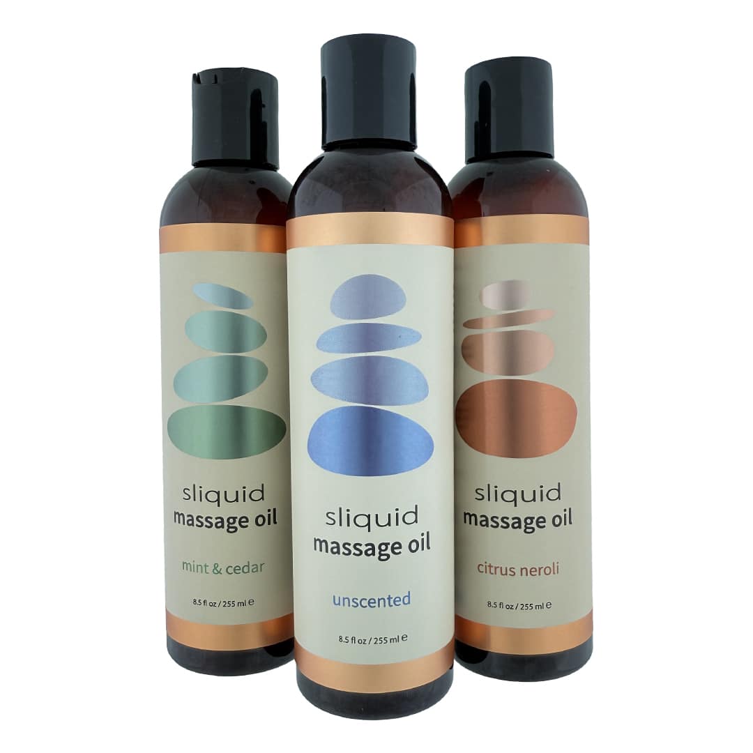 Three bottles of sliquid massage oil with different scents on a white background