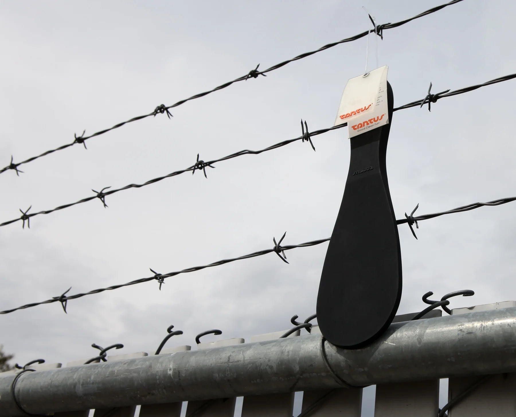Tantus Pelt Silicone Paddle with a brand logo on a barbed wire fence