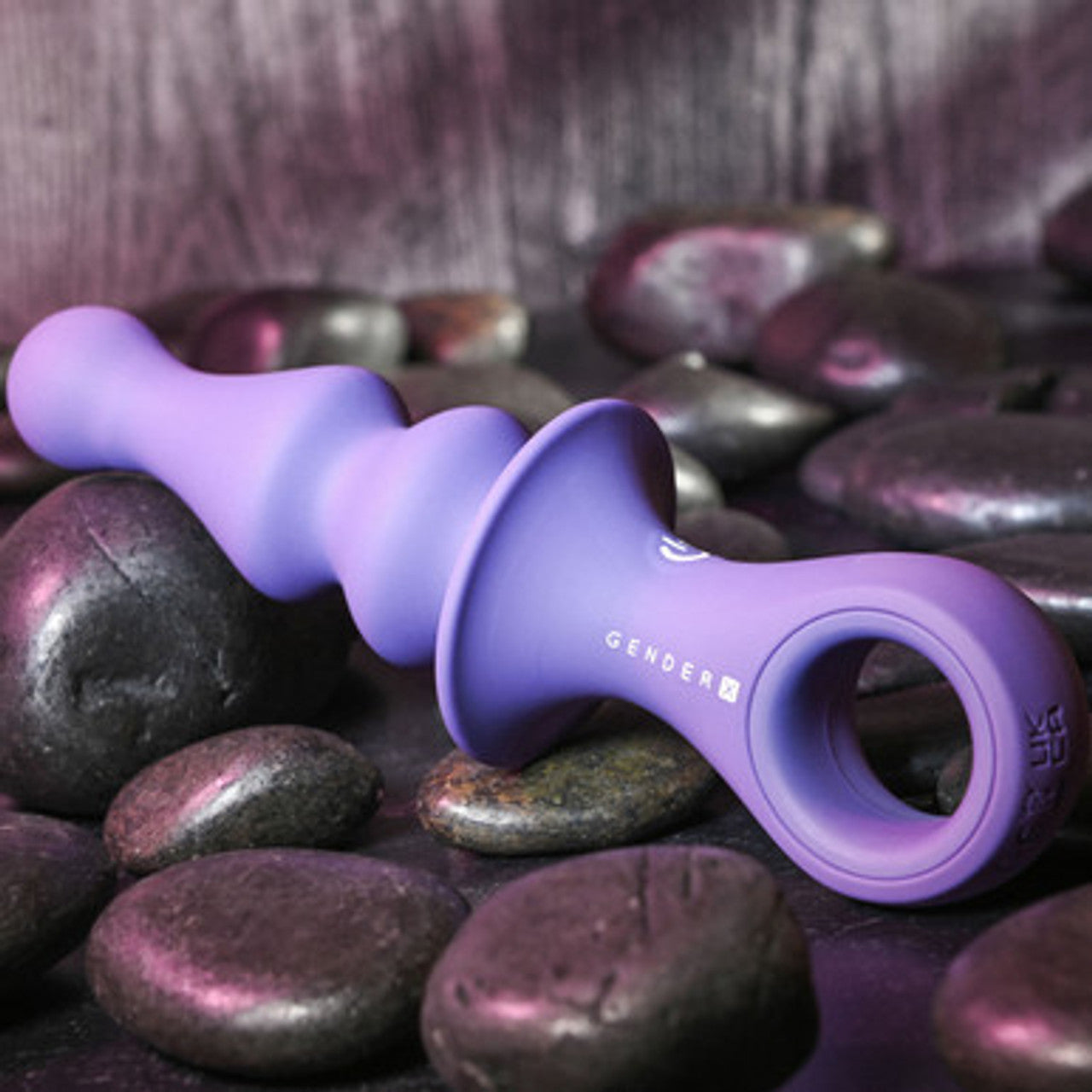 Purple Gender X Ring Pop sex toy on purple stones