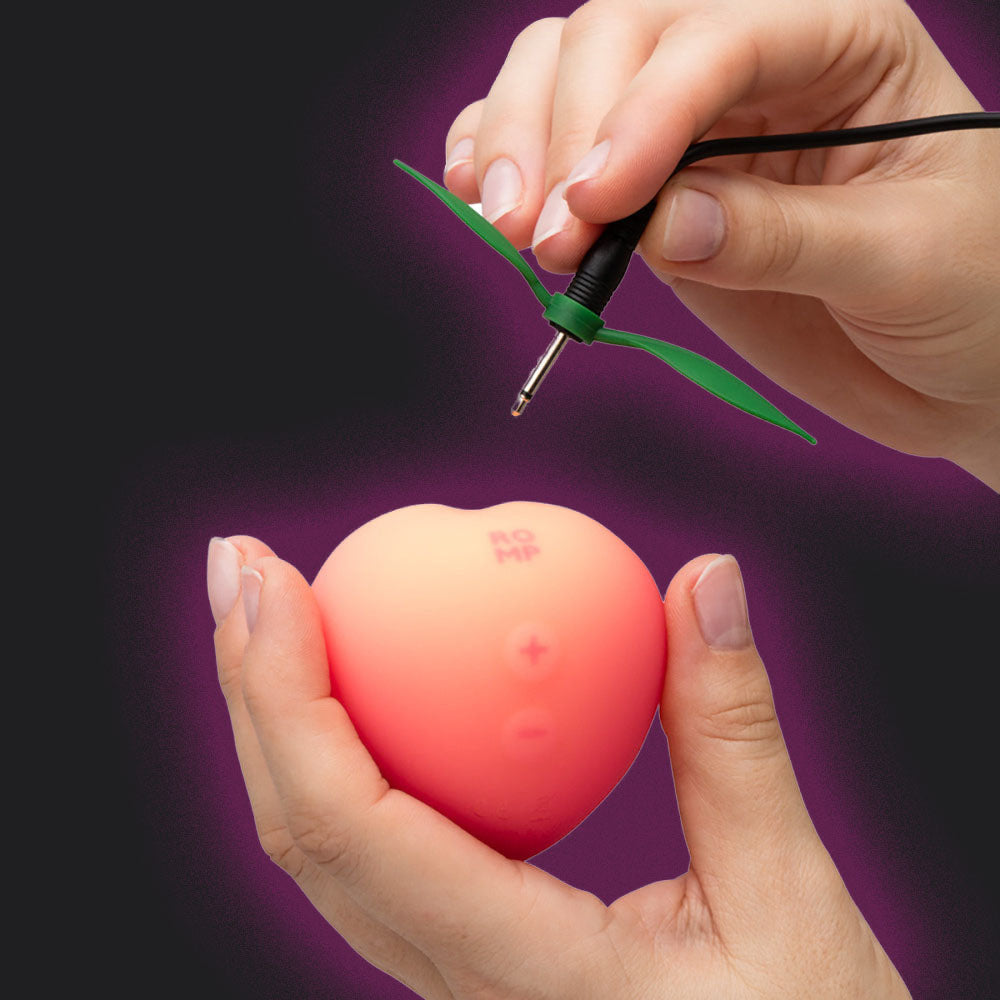 Person using Romp Pink Peach Vibrator against a purple background