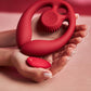 Red handheld SVibe Snail GIZI Duo Double Ended Dildo And Vibe held in hands against a pink background