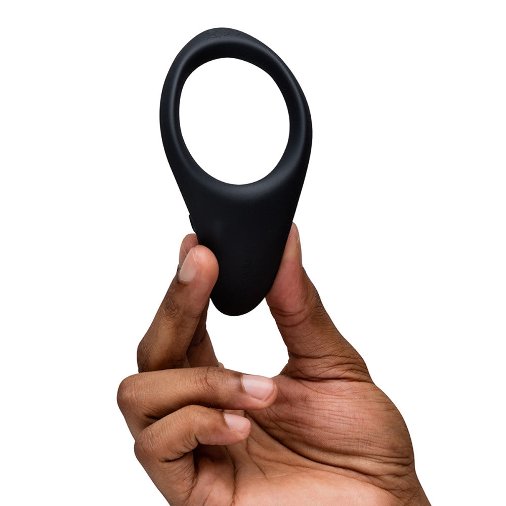 Hand holding a black silicone ring against a white background