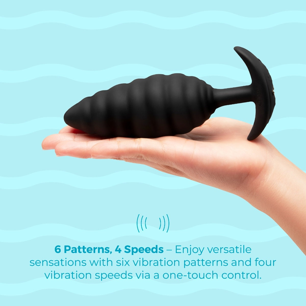 Black silicone butt plug held in a hand against a light blue background